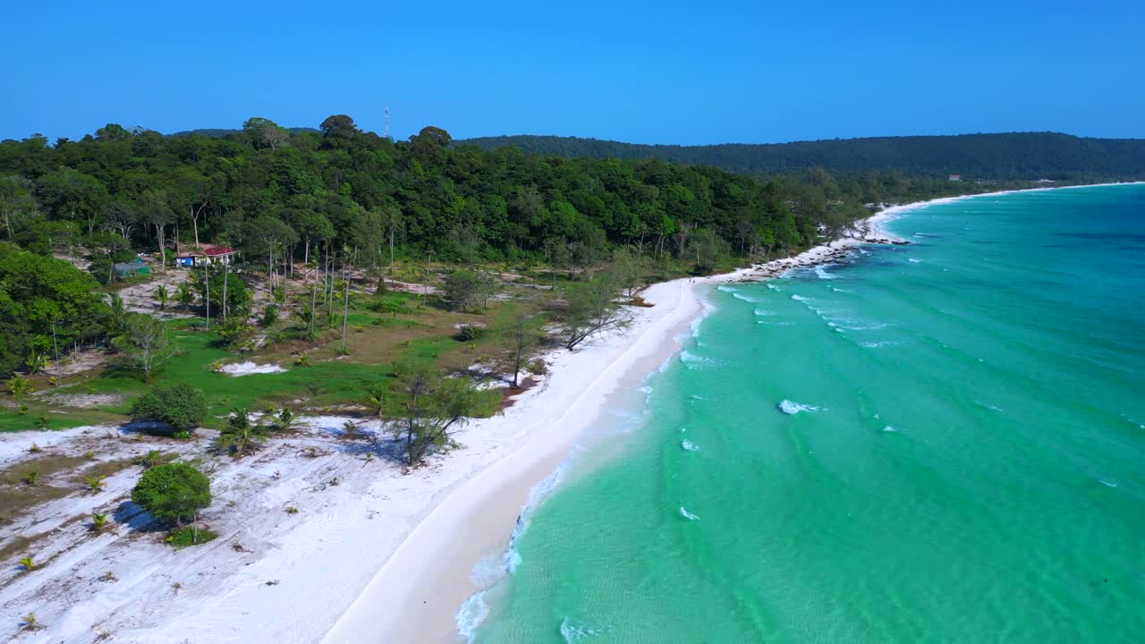 Black Stones in turquoise water gently washing the white sand beach of Koh Rong island, cambodia, on a sunny day with clear blue sky. Stunning aerial view flight overflight flyover drone