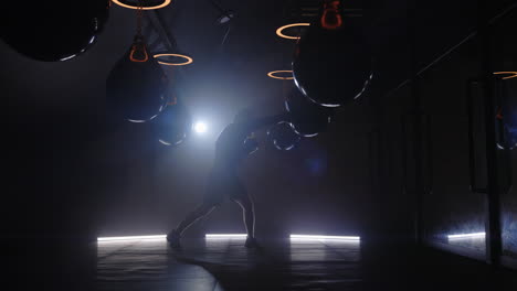 Silhouette of a boxer training in a gym with punching bags