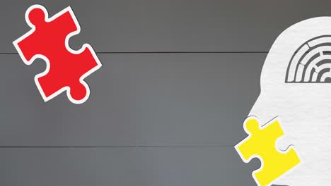 animation of green, yellow and red puzzle pieces falling over model of human head on grey background