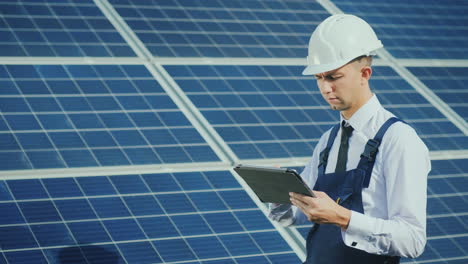 a young engineer works at a solar power station uses a tablet