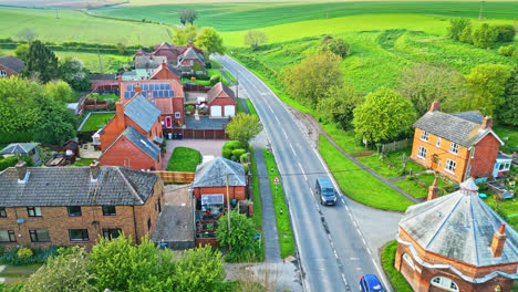 Burwell-village,-a-medieval-market-town-in-the-past,-is-portrayed-through-drone-imagery,-featuring-rural-fields,-aged-red-brick-residences,-and-the-abandoned-Saint-Michael-parish-church