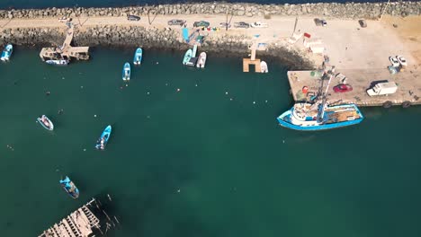 aerial pullback tilt up along cedros island docks and fishing boats, showcasing local marine activity and scenic views