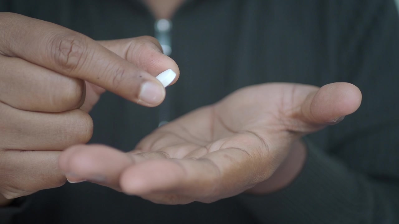 Person Holding and Picking Up a White Pill