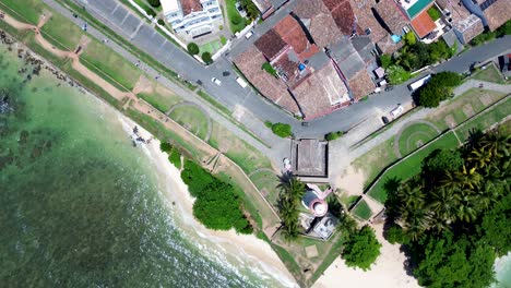 Aerial-drone-landscape-of-Galle-lighthouse-and-apartment,-hotel-and-shops-rooftops-in-street-historic-Dutch-old-town-square-Sri-Lanka-travel-tourism-Asia