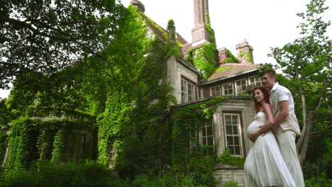 pregnant couple hugging near country house. love couple near old house.