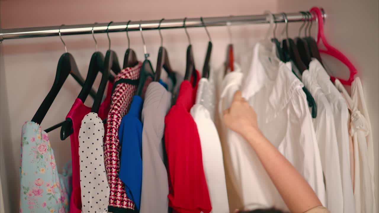 Close-up of Female Hands Plucked Hanger choosing clothes in wardrobe