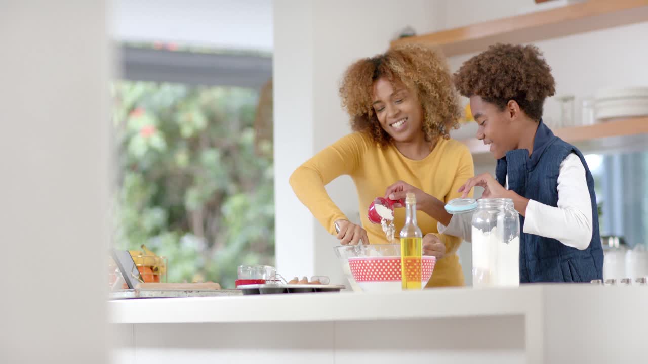 Happy african american mother and son baking in kitchen, slow motion