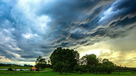 timelapse chmur burzowych poruszających się po niebie nad małym domkiem rolnym i polami