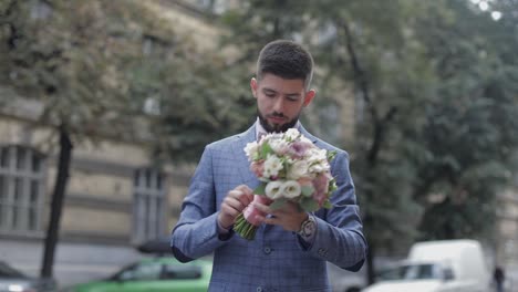 Groom-with-a-black-beard-with-wedding-bouquet-on-the-street.-Wedding-day