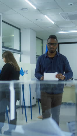 Multiethnic-European-people-vote-in-voting-booths-at-polling-station-during-EU-elections.-Caucasian-male-voter-puts-ballot-paper-in-box.-Election-Day-in-the-European-Union.-Civic-duty-and-democracy.