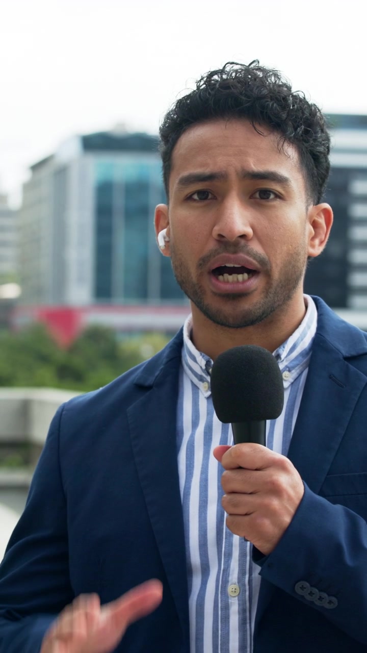 Reporter uomo che parla al microfono all'aperto in città