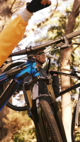 mountain biking couple carrying bicycle and pointing at nature