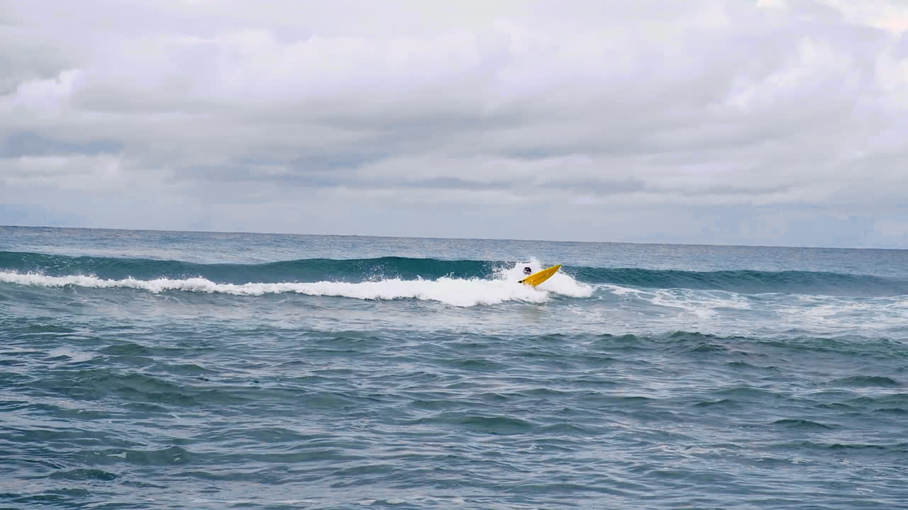 균형을 잡으려고 작은 파도에서 서핑하는 사람이 필리핀의 잔잔한 푸른 바다에서 쓰러졌습니다.