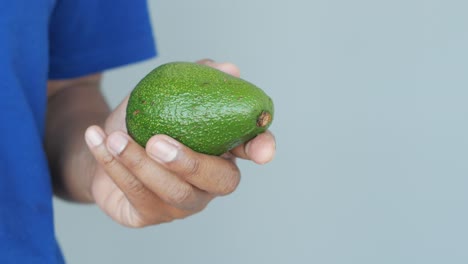 persona que sostiene un aguacate maduro