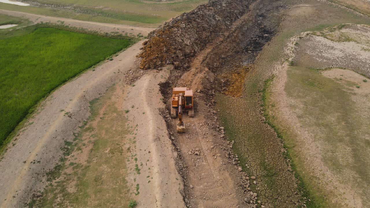 тяжелый желтый экскаватор чистит канаву в бангладешском пейзаже, вид с орбиты с воздуха