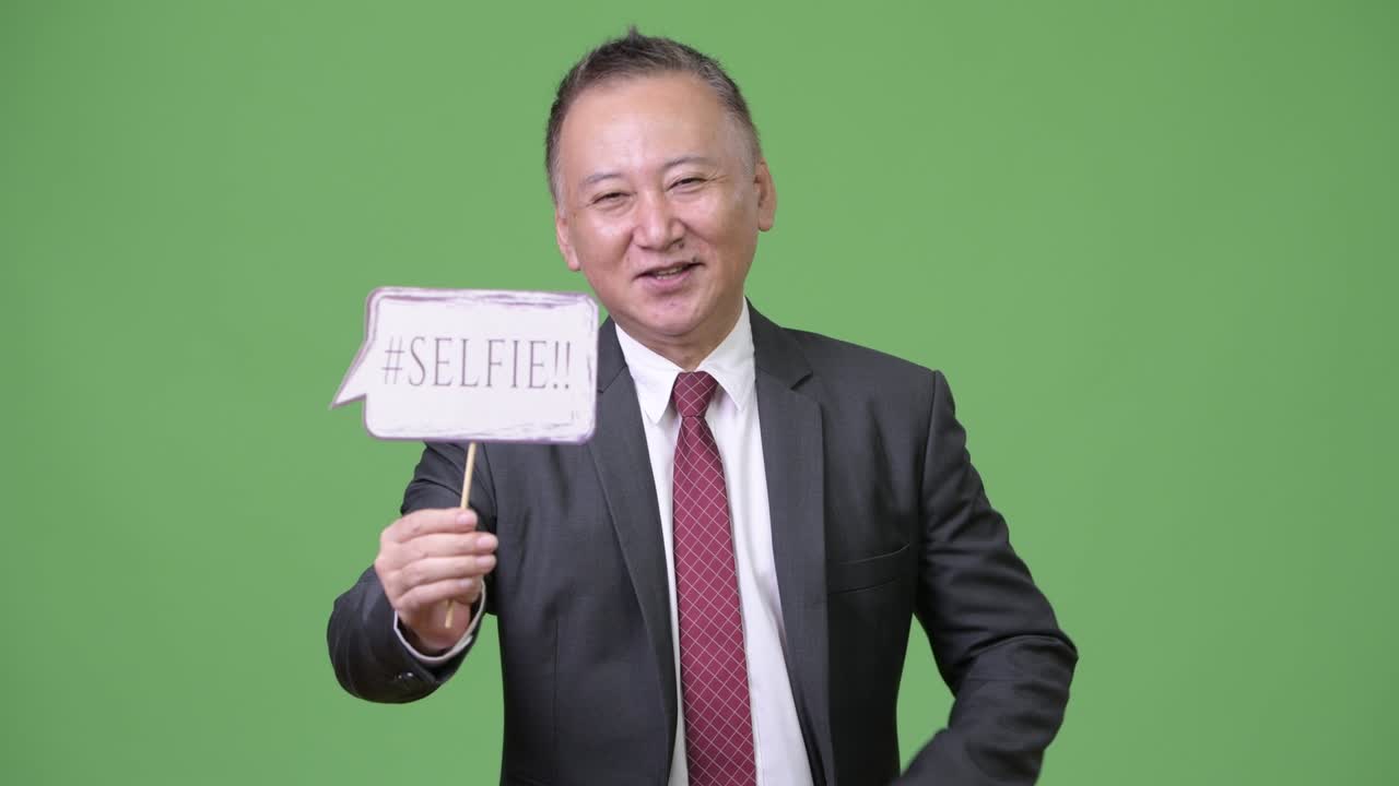 성숙 한 일본인 사업가 가 종이 표지판 을 들고 있다