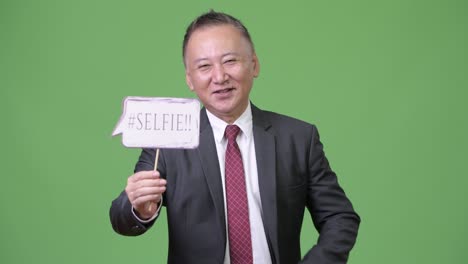 성숙 한 일본인 사업가 가 종이 표지판 을 들고 있다