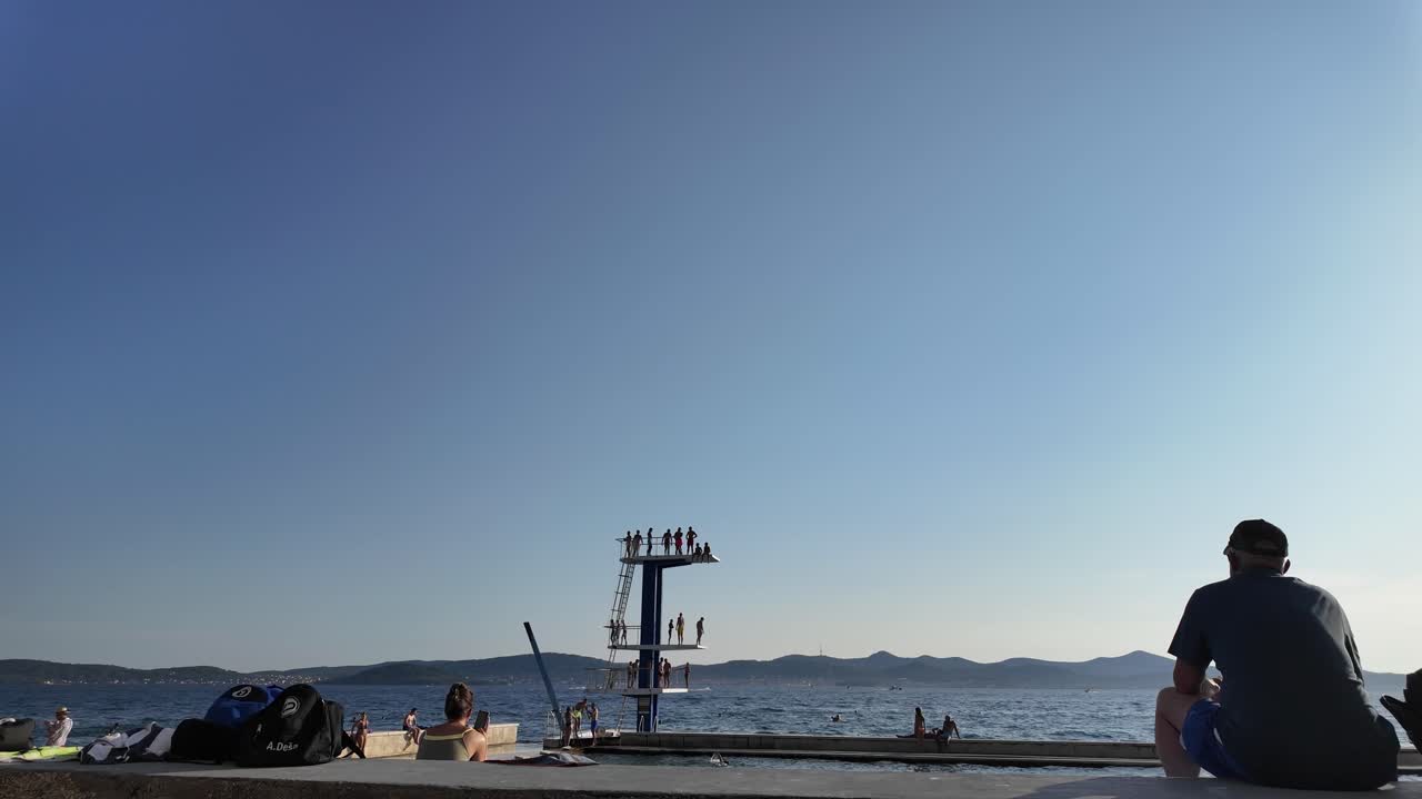 People enjoying a summer day at a coastal diving platform