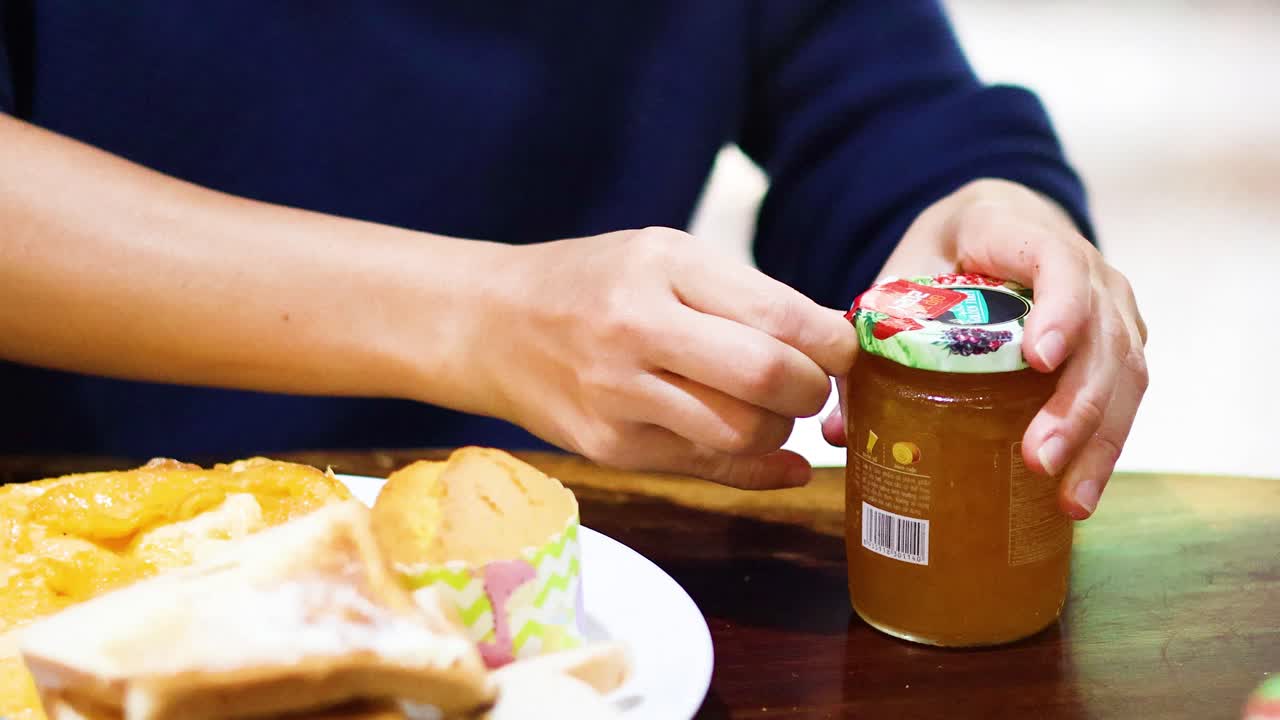 manos abriendo frasco con comida en la mesa