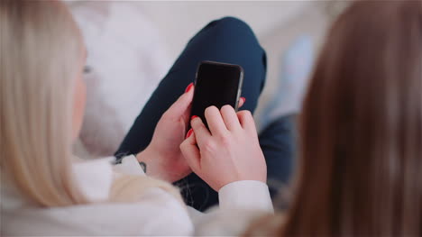 Two-Young-Womans-Doing-Online-Shopping-On-Smartphone-Browsing-Internet-Social-Media