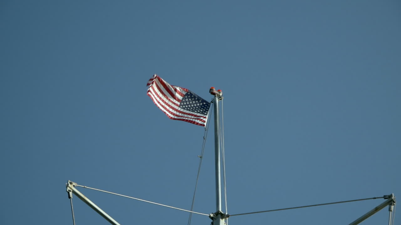 Et amerikansk flag monteret på toppen af en skibsmast, der vajer i vinden