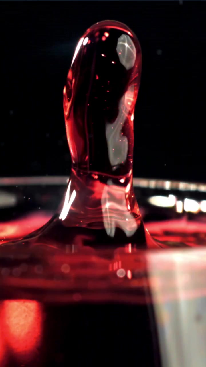 Goccia di liquido rosso che cade e schizza al rallentatore