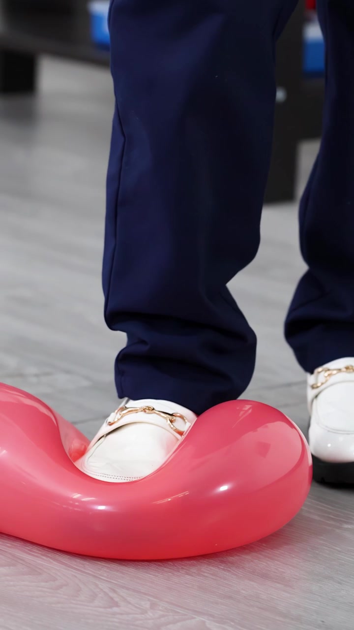 Close-up seorang anak bers sepatu putih menginjak balon merah selama eksperimen STEM di kelas.