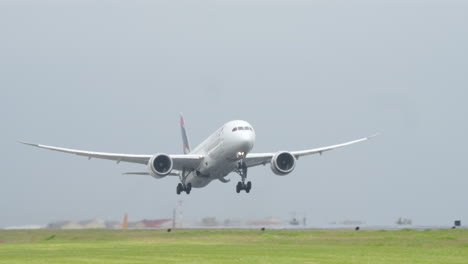 lisbon, portugal - april 7, 2025: frontal view of a latam airlines boeing 787 dreamliner aircraft taking off from lisbon airport. the wide-body jet is seen mid-air with landing gear extended and engines active under cloudy skies