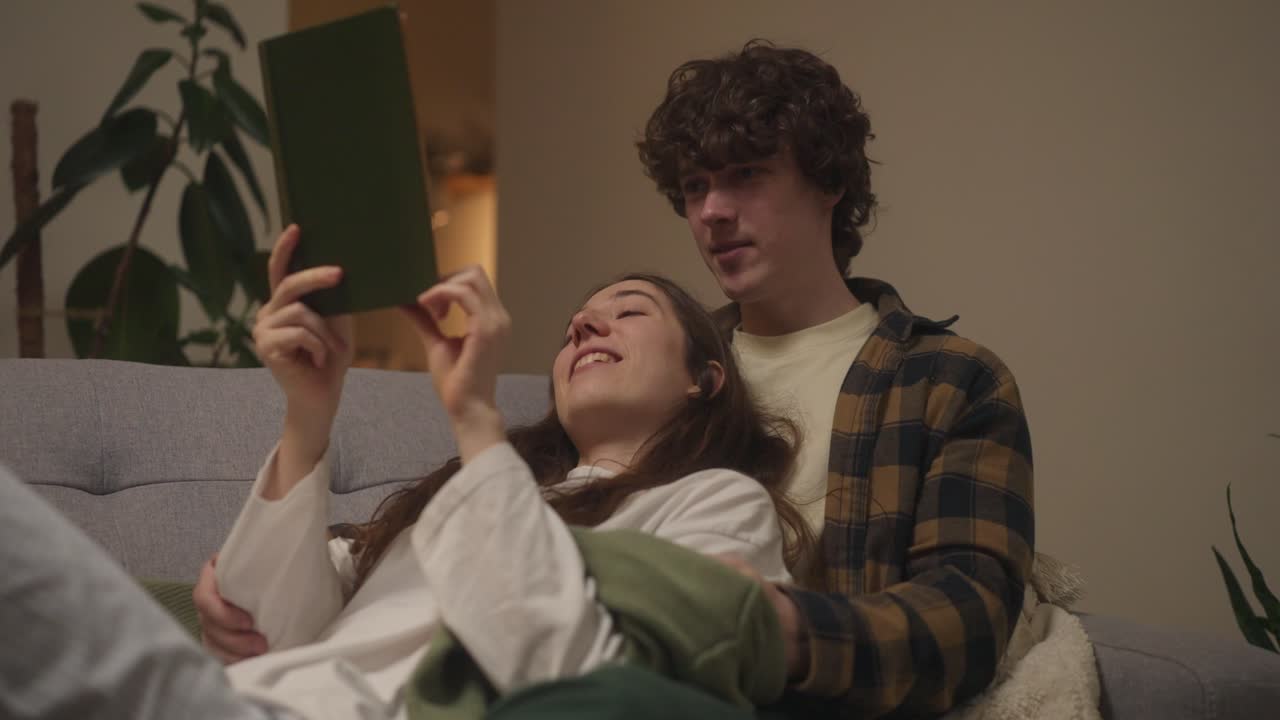 pareja leyendo un libro juntos en el sofá