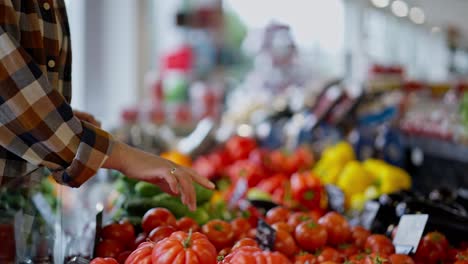 Close-up-a-girl-in-a-checkered-shirt-sorts-out-ripe-vegetables-with-her-hands-on-a-vegetable-counter-in-a-supermarket