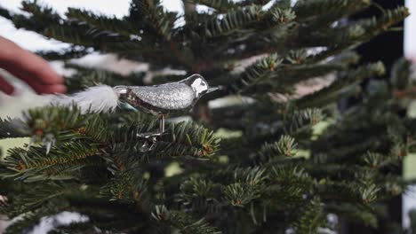 pájaro de plata de fantasía con decoración de cola blanca en el árbol de navidad verde