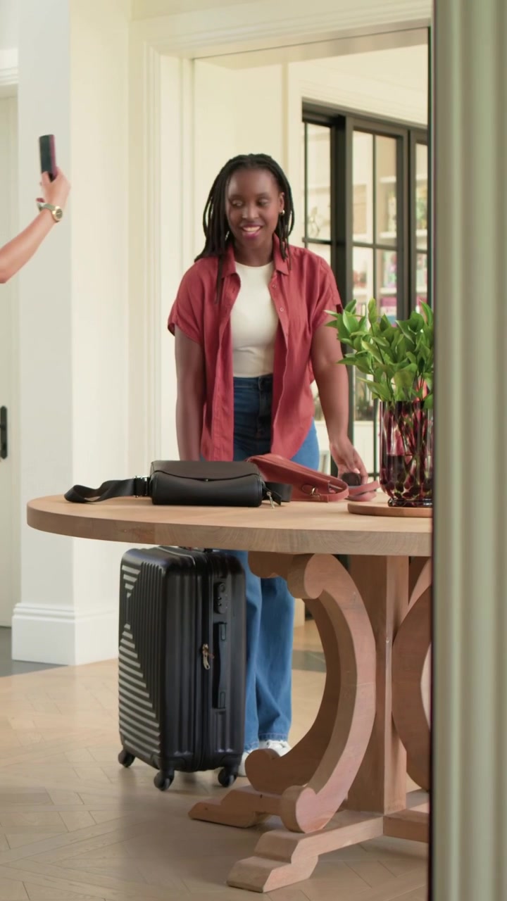 Vertical video: Entering foyer trio in rust shirt pulling suitcases taking phone selfie settling in