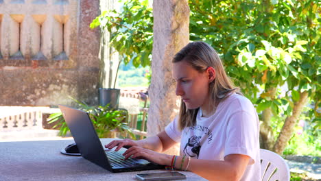 Mujer-Enfocada-Teletrabajando-Escribiendo-En-Una-Computadora-Portátil-En-El-Jardín