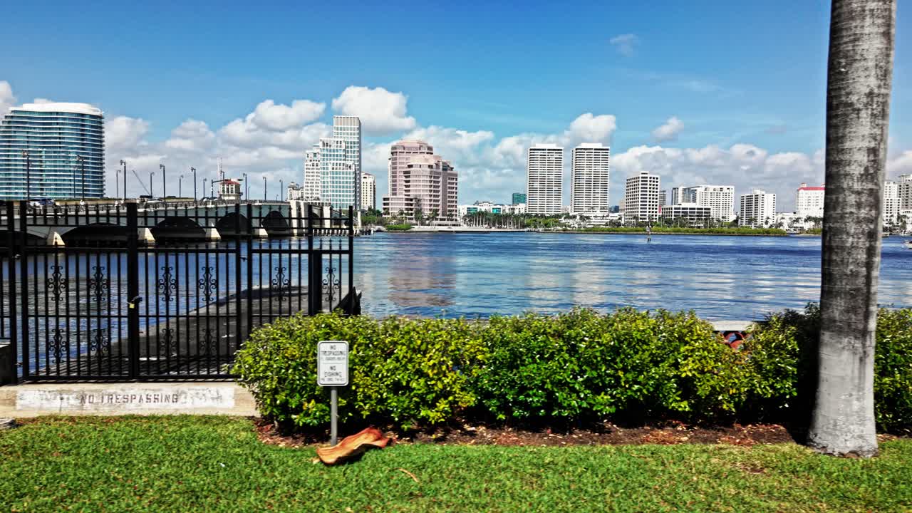 Aerial: cityscape from parking lot with Royal Park Bridge, One Flagler and Phillips Point building during the day in West Palm Beach, Florida, USA, pan drone shot