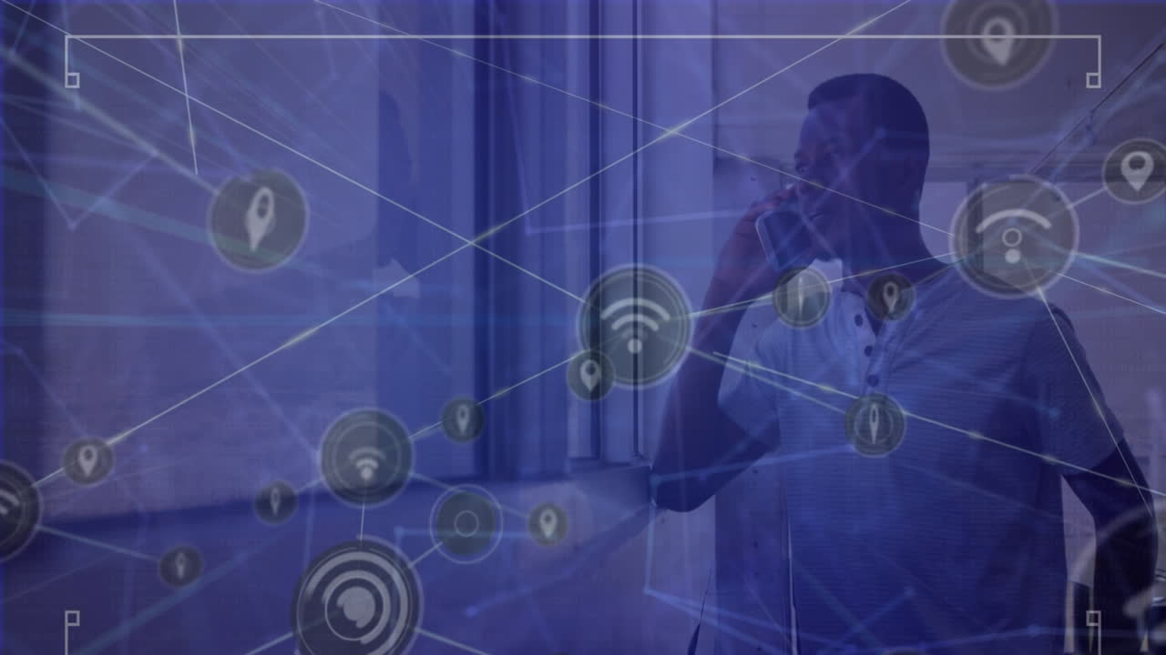 Animation of network of digital icons over african american man talking on smartphone near a window