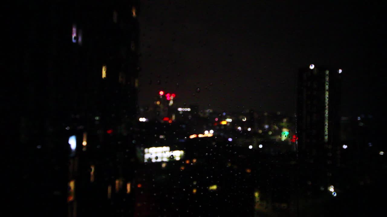 Water running down a window with a blurred out city in the background