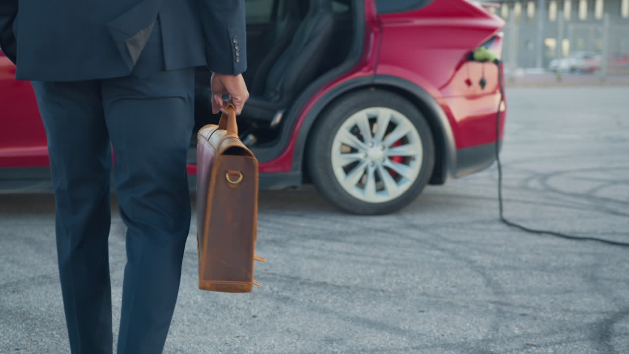 homem de negócios com maleta perto de um carro elétrico