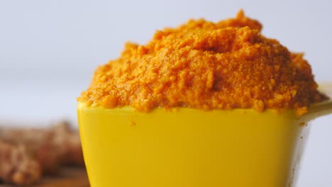 turmeric root and paste in a bowl on white background ,