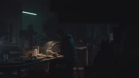 a bombmaker assembles a bomb in his workshop at night