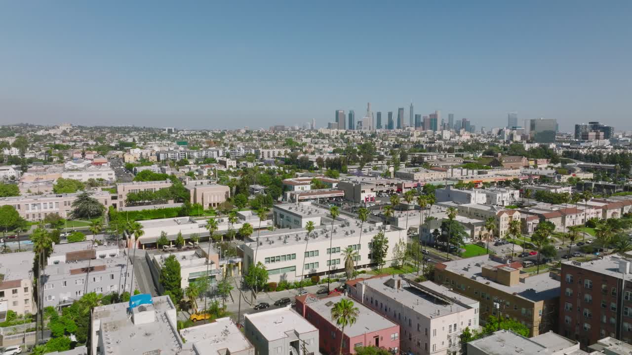 Volo su Los Angeles in una giornata soleggiata in California, tetti sottostanti e skyline della città davanti