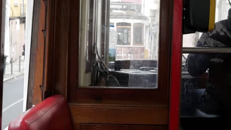 driver cabin in a lisbon tram commute. ride around the european city streets. vintage wooden cabin interior and red leather seats. driver spins speed control handle. other controls on dashboard.