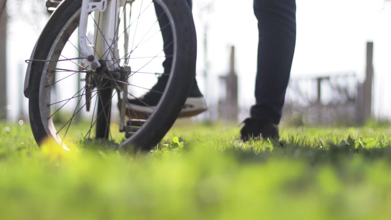 Person pushing a white bike on a meadow. Old bicycle.