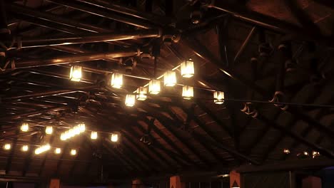 Arc-Shot-Of-Distinctive-Lighting-Design-Suspended-From-Metal-Bars-At-Wedding-Dinner