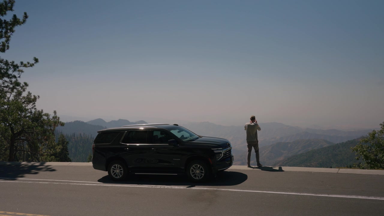 Un SUV nero percorre una strada panoramica di montagna sopra una valle fosca.