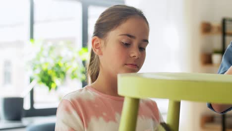 furniture-renovation,-diy-and-home-improvement-concept--happy-smiling-mother-and-daughter-sanding-old-round-wooden-chair-with-sponge-at-home