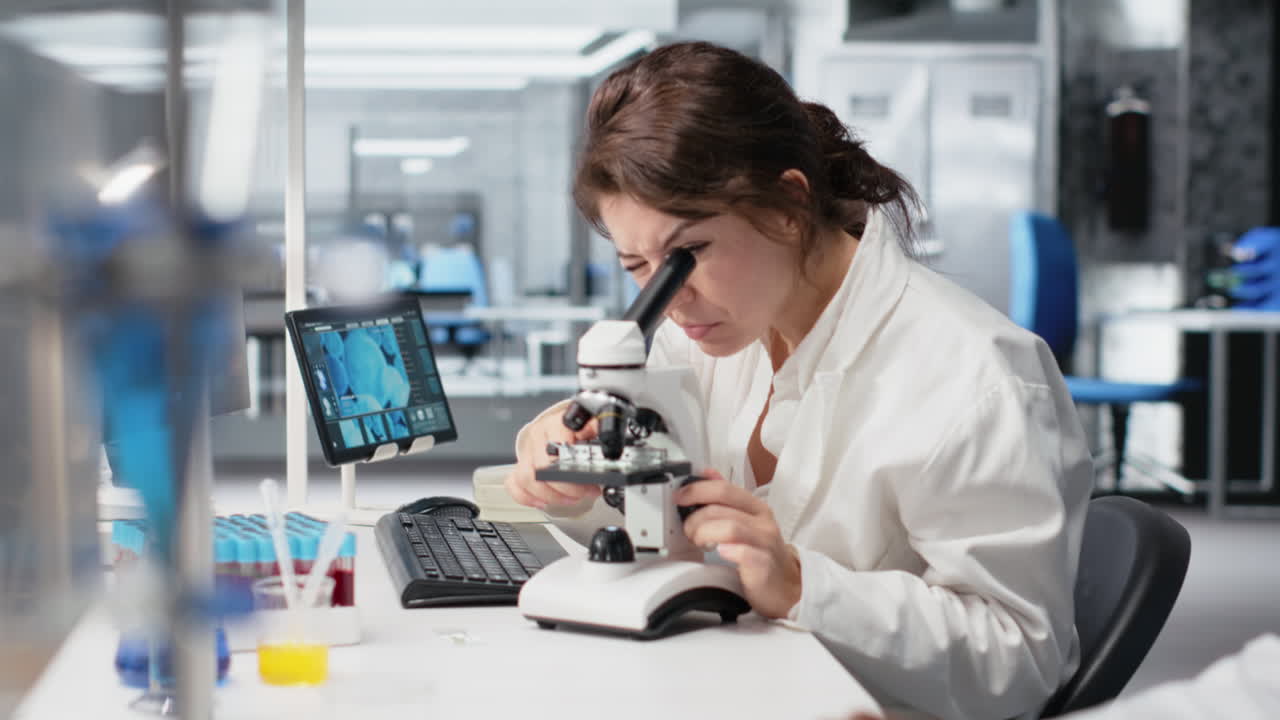 Vertical video Zoom in on histology technician in lab using scientific microscope