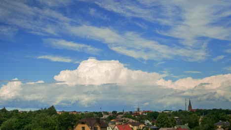 time lapse of beautiful white fast moving puffy cumulus clouds on a sunny summer day, cityscape with rooftops, distant wide shot