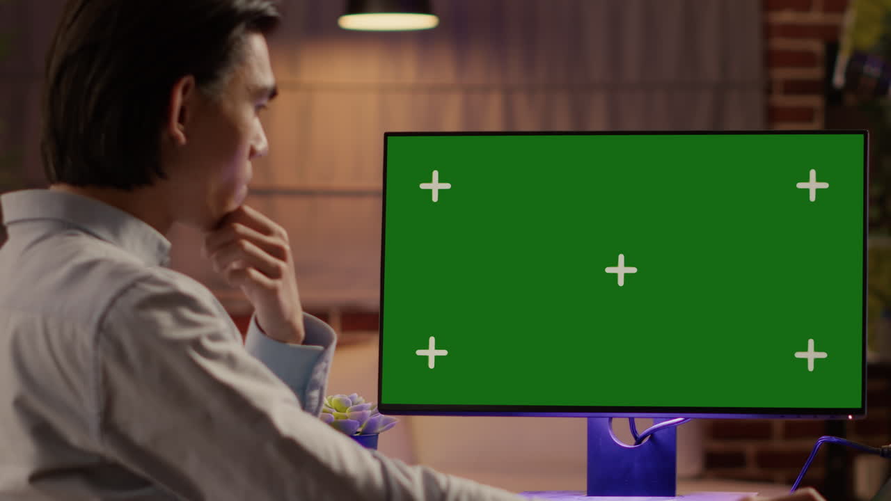 Man working on computer with green screen monitor