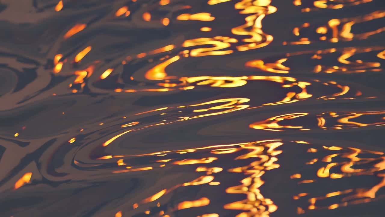 Close-up video of golden light reflections on rippling water, captured from a low angle