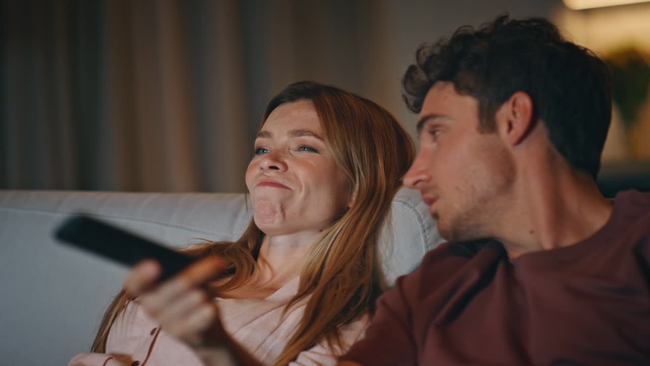 Closeup lazy lovers chilling sofa watching tv evening home. Man turning channels